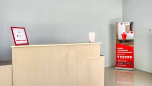 A hotel reception desk with a framed 'Partner' sign, a RedDoorz promotional stand, and a clean, modern interior. - RedDoorz @ Jalan Kapten Muslim Medan (Medan)