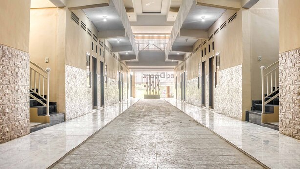 A long, narrow hallway with a tiled floor and a high ceiling with recessed lighting. - RedDoorz @ Jalan Kapten Muslim Medan (Medan)