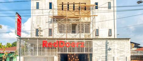 Un edificio con un letrero que dice "RedDoorz" y un letrero rojo a la izquierda.