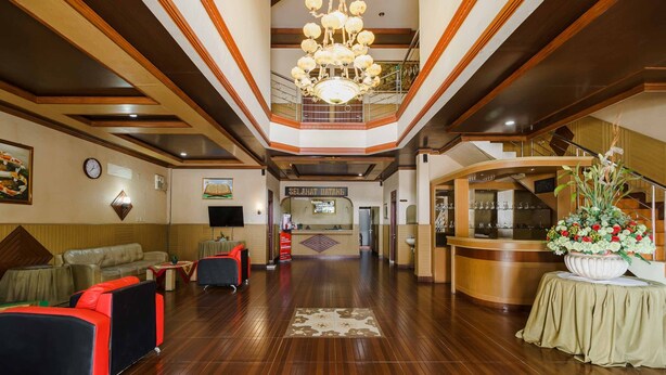A lobby with a reception desk, seating area, and a staircase.