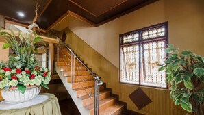 A staircase with a metal handrail, a large floral arrangement on a table, and a window with decorative bars.