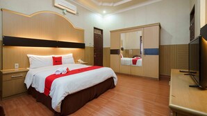 A hotel room with a large bed, a wardrobe, a TV, and a mirror.