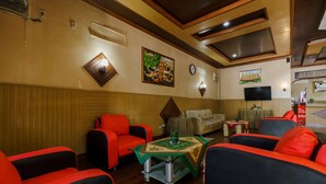 A hotel lobby with red and black sofas, a green and white patterned table, and a clock on the wall.