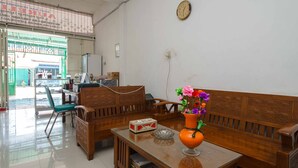 A room with a wooden bench, a small table with a vase of flowers, and a clock on the wall. - RedDoorz Syariah near Stasiun Kereta Api Kisaran (West Kisaran)