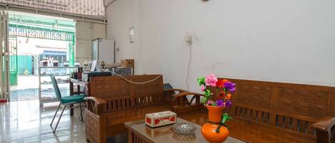 Una habitación con un banco de madera, una mesa pequeña con un florero y un reloj en la pared.