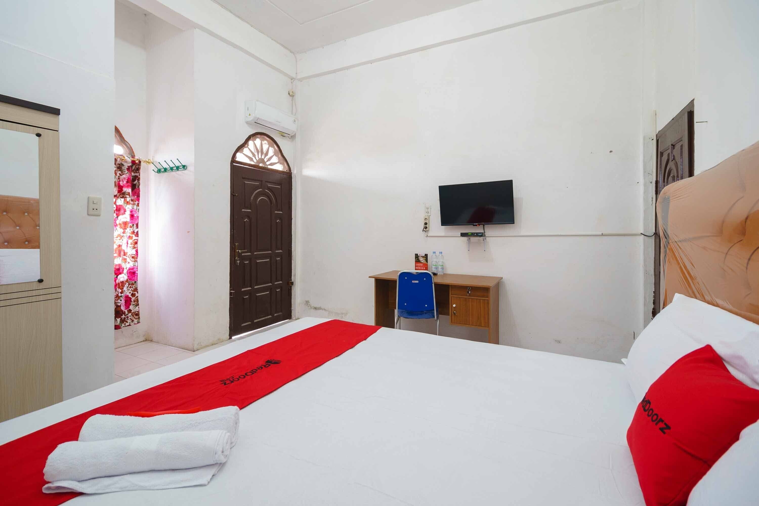 A hotel room with a bed, a TV, a desk, and a chair.