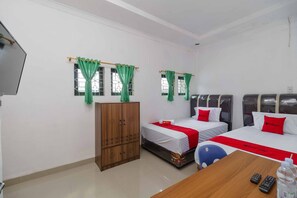 A hotel room with two beds, a wooden wardrobe, a desk with a chair, and a TV.