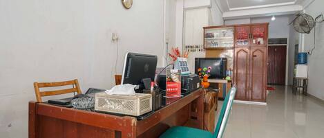 Una habitación con un escritorio de madera, una computadora, una silla y un mueble con puertas de vidrio.