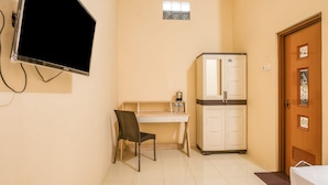 A small room with a desk, chair, and a refrigerator. - RedDoorz Syariah near Kebon Rojo Park Blitar (Blitar)