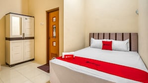 A hotel room with a bed, a wardrobe, and a door. - RedDoorz Syariah near Kebon Rojo Park Blitar (Blitar)