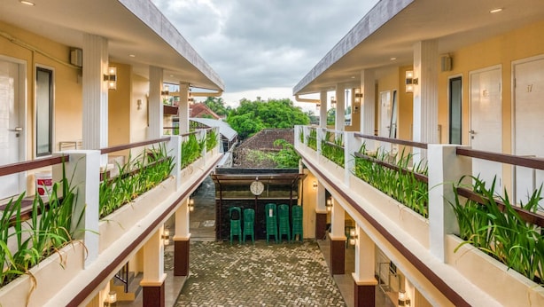 A corridor with two-story rooms, each with a balcony and a view of greenery. - RedDoorz Syariah near Kebon Rojo Park Blitar (Blitar)