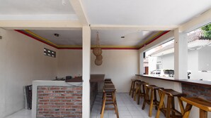 A kitchen with a brick accent wall, wooden stools, and a hanging light fixture. - RedDoorz @ Raya Janti Yogyakarta (Baturetno)