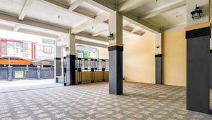 Un espacio interior amplio con piso de baldosas estampadas, pilares grandes y una reja de metal.