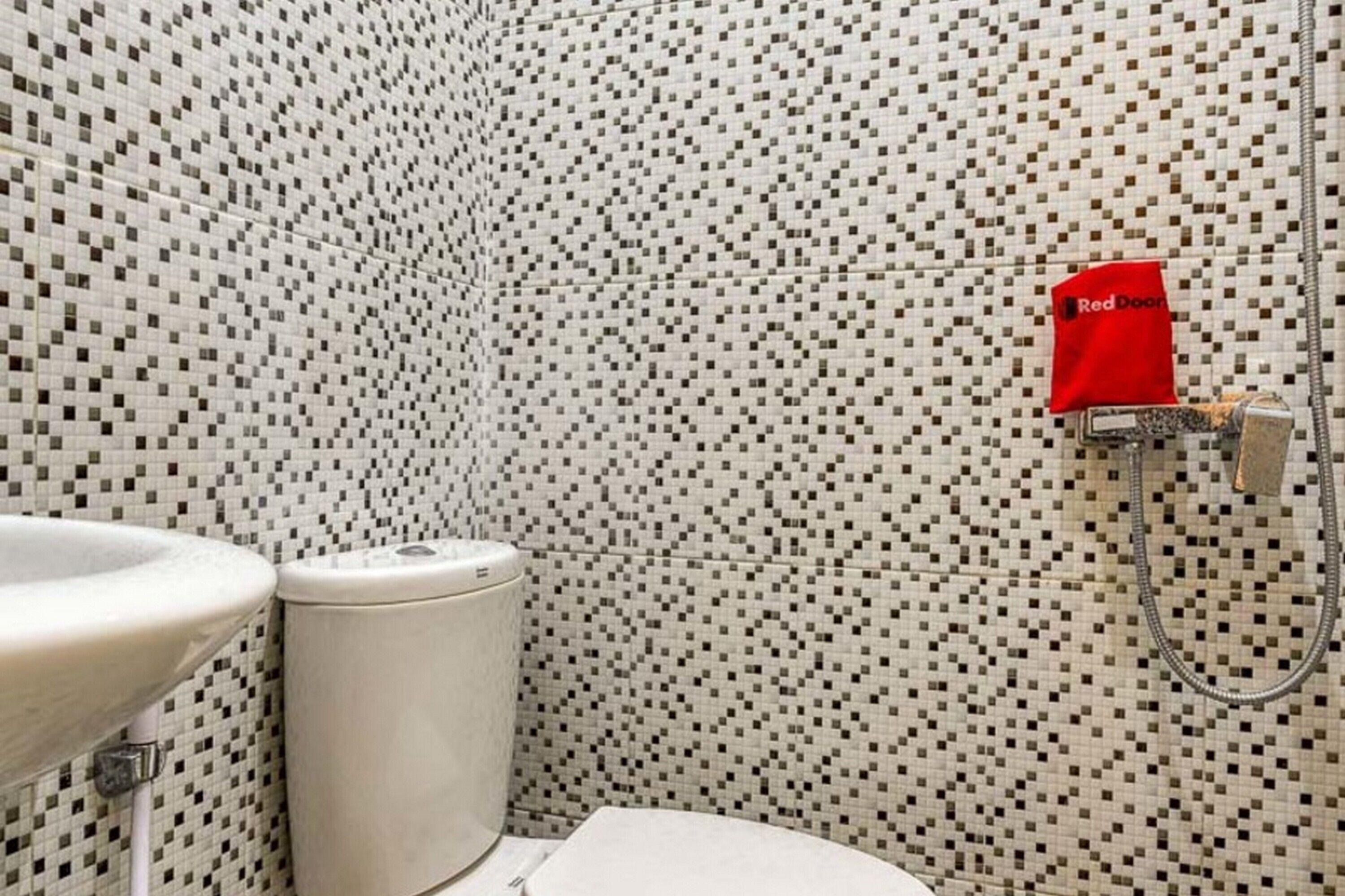 A bathroom with a tiled wall, a toilet, and a sink.