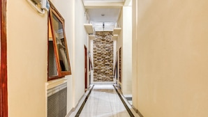 Un pasillo estrecho con una pared de piedra al final, flanqueado por puertas de madera y un radiador.