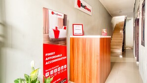 Un área de recepción con un letrero de RedDoorz, un cartel de RedDoorz y un certificado de socio de RedDoorz.