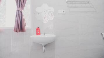 A bathroom with a white sink, a red bottle, and a towel rack.