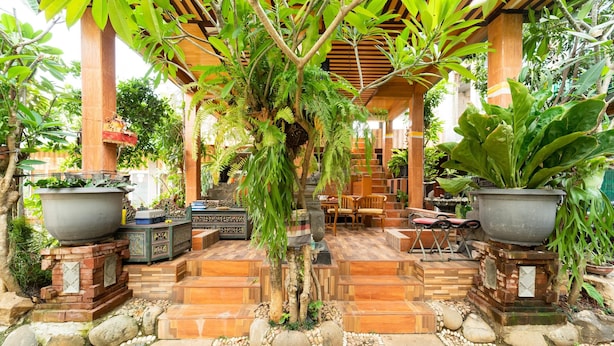 A covered outdoor area with a wooden pergola, stone steps, and potted plants. - KoolKost near University of Indonesia (Depok)