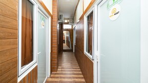A hallway with wooden paneling, a tiled floor, and signs indicating room numbers and amenities. - KoolKost near University of Indonesia (Depok)
