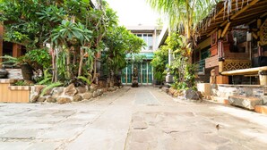 A stone-paved courtyard with a central pathway, surrounded by lush greenery and traditional architecture. - KoolKost near University of Indonesia (Depok)