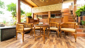 A wooden outdoor seating area with a table and chairs, surrounded by a wooden fence and potted plants. - KoolKost near University of Indonesia (Depok)