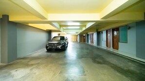 Un pasillo largo y estrecho con un automóvil estacionado en el centro. Las paredes están pintadas de un color claro y el piso es de concreto.