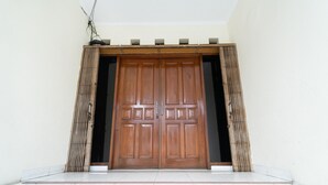 Una puerta doble de madera grande con un sistema deslizante, ubicada en una pared lisa con suelo de baldosas.