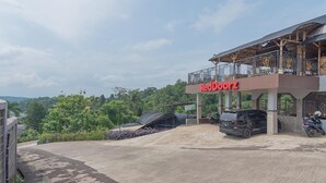 Un edificio RedDoorz con un área exterior cubierta, una camioneta SUV estacionada y una motocicleta.