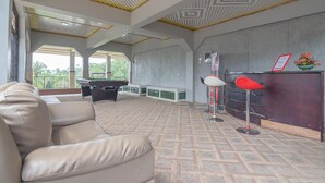 Amplio espacio interior con techo alto, una recepción, una silla roja y un sofá beige.