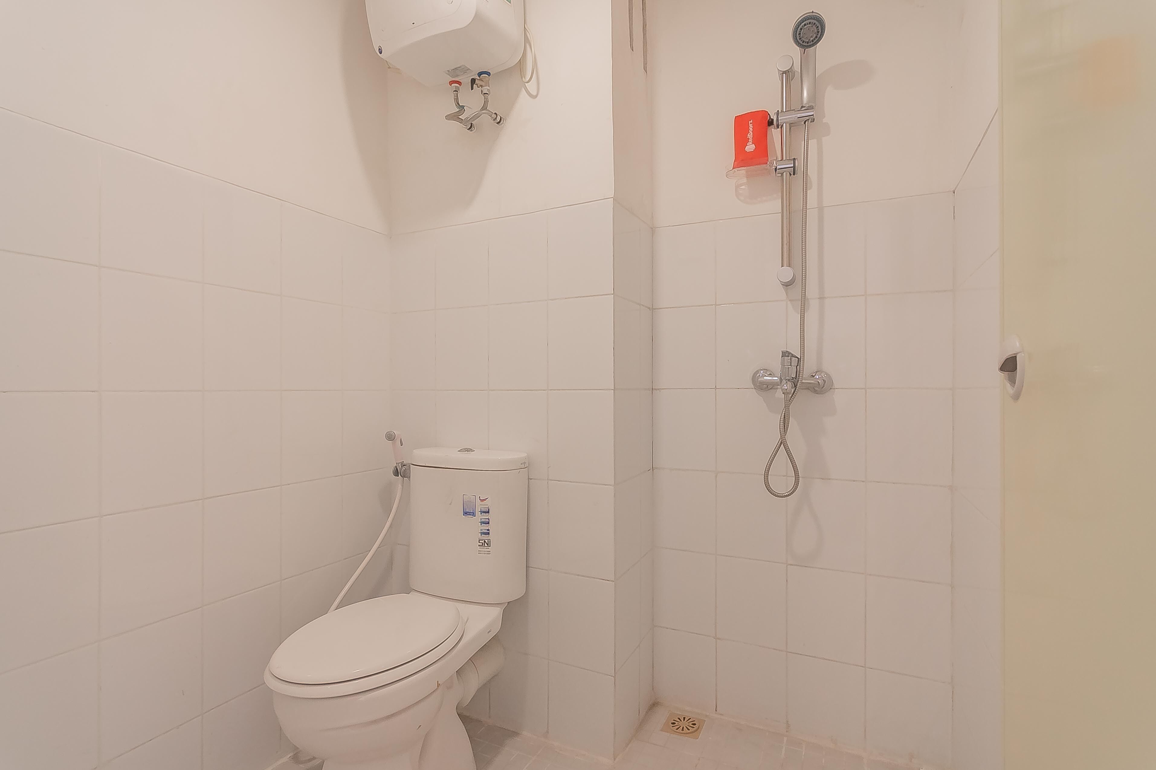 A small, clean bathroom with a white toilet, a shower, and a hand dryer.