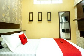 A hotel room with a bed, a red pillow, a white pillow, a red throw, and three black-framed mirrors on the wall. - RedDoorz near Benteng Van Den Bosch (Ngawi)