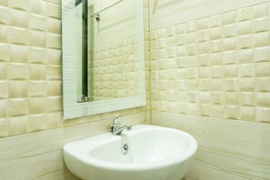 A bathroom with a white sink, a mirror, and beige textured walls. - RedDoorz near Benteng Van Den Bosch (Ngawi)