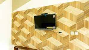 Un téléviseur fixé au mur, avec un motif géométrique en bois.