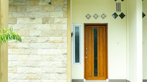 Un couloir avec un mur en pierre, une porte en bois et des carreaux décoratifs.