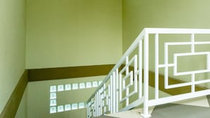Un escalier doté d’une rampe blanche aux motifs géométriques et d’une fenêtre à carreaux.