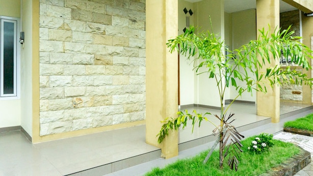 Un bâtiment doté d’une façade en pierre, d’un espace d’entrée abrité et d’un petit jardin avec de la pelouse et des plantes.