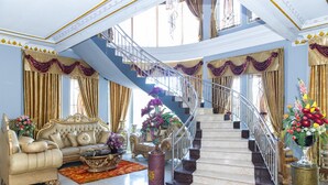 A grand interior with a luxurious sofa, a staircase, and elegant decor. - RedDoorz Premium @ Sea Residence Manado (Manado)