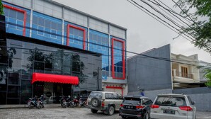 Ein Gebäude mit roter Markise, abgestellten Motorrädern und Autos.