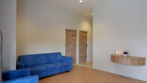 Ein modernes Wohnzimmer mit einem blauen Sofa, Holzboden und einer eingebauten Regalanlage mit Kerzen.