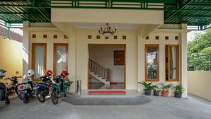 A building entrance with a staircase, potted plants, and parked motorcycles.