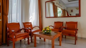 A room with four wooden chairs, a glass-top table, and a large mirror on the wall.