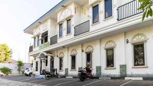 A two-story building with a white facade, multiple windows, and a sign that reads "The Garden." There are two scooters parked in front. - RedDoorz Plus @ Jalan Pumorow Manado (Manado)