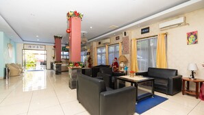 A hotel lobby with black leather sofas, a coffee table, and a reception desk. - RedDoorz Plus @ Jalan Pumorow Manado (Manado)