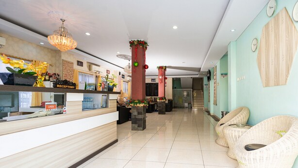 A reception area with a counter, chairs, and a staircase in the background. - RedDoorz Plus @ Jalan Pumorow Manado (Manado)