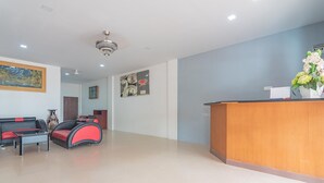A reception area with a wooden desk, a sofa, and a chair. - RedDoorz @ Pasar Melayu Sagulung Batam (Batam)