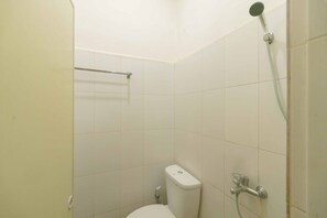 A small, clean bathroom with white tiles, a toilet, a shower with a handheld showerhead, and a towel rack. - RedDoorz @ Haraito Tarutung (Hutagodang)