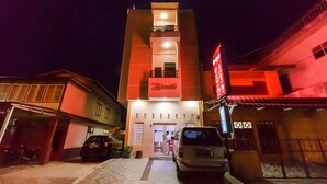 A hotel with a central entrance, a balcony on the second floor, and a red sign above the entrance.