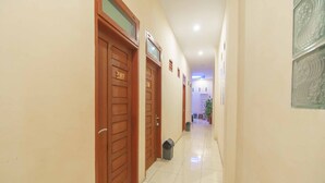 A hallway with wooden doors, a trash bin, and a tiled floor.