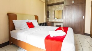 Ein Hotelzimmer mit einem Bett, einem Holzschrank, einem Spiegel und einem kleinen Tisch.