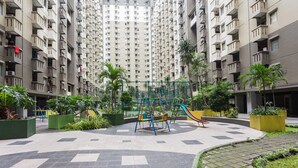 Ein Spielplatz mit Schaukeln und Rutschen, umgeben von Grünflächen und Wohngebäuden.